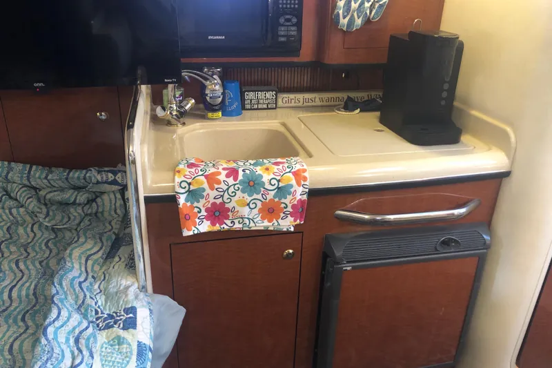 Slide: The Image of 2004 Sea Ray 280 Sundancer cabin with kitchenette, sink, and colorful towel. - 18