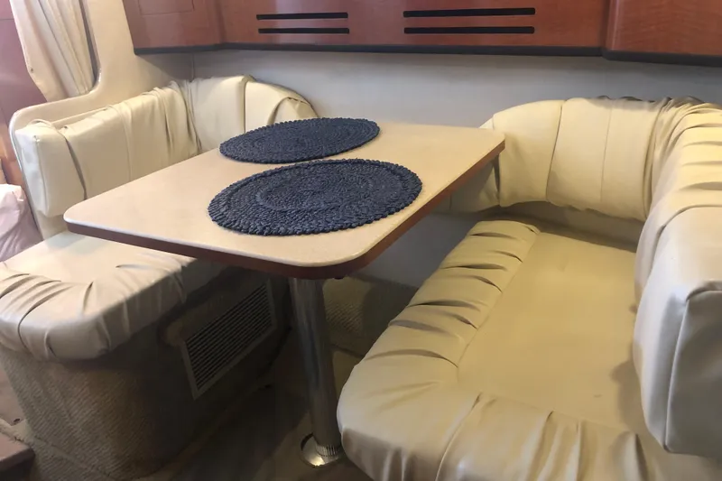 Slide: The Image of 2004 Sea Ray 280 Sundancer cabin dining area with cushioned seating and table. - 20