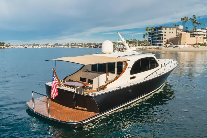 Slide: The Image of 2015 Palm Beach Motor Yachts 45 Sedan cruising near a coastal cityscape. - 10