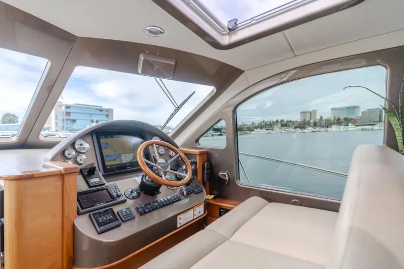 Slide: The Image of 2015 Palm Beach Motor Yachts 45 Sedan interior with helm, steering wheel, and waterfront view. - 12