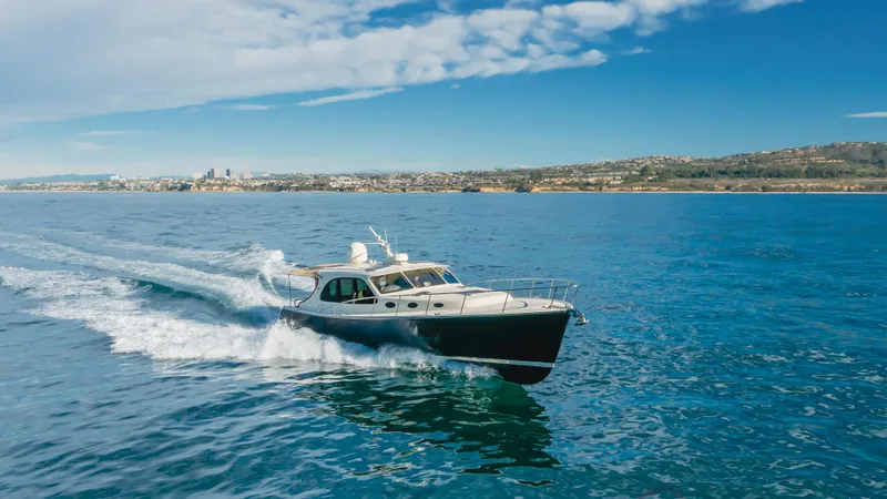 Slide: The Image of 2015 Palm Beach Motor Yachts 45 Sedan cruising on open water under a clear blue sky. - 14