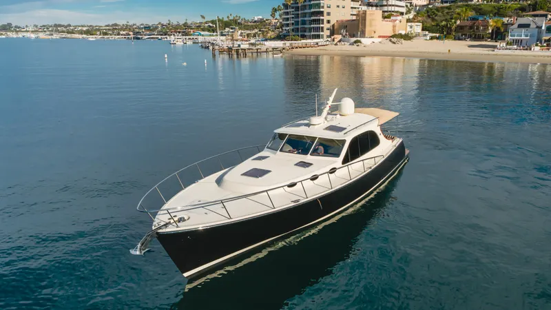 Slide: The Image of 2015 Palm Beach Motor Yachts 45 Sedan cruising near a coastal shoreline. - 40