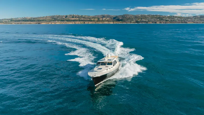 Slide: The Image of 2015 Palm Beach Motor Yachts 45 Sedan cruising on open water with scenic coastline backdrop. - 51