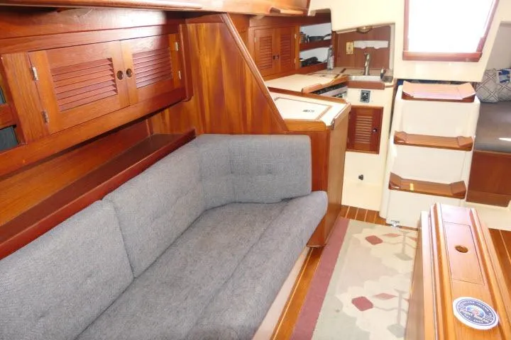 Slide: The Image of Interior of a 1995 Tartan 3100 sailboat with wooden cabinetry and gray sofa. - 10