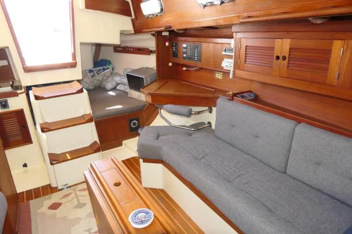 Slide: The Image of Interior of a 1995 Tartan 3100 sailboat with wooden cabinetry and gray seating. - 11