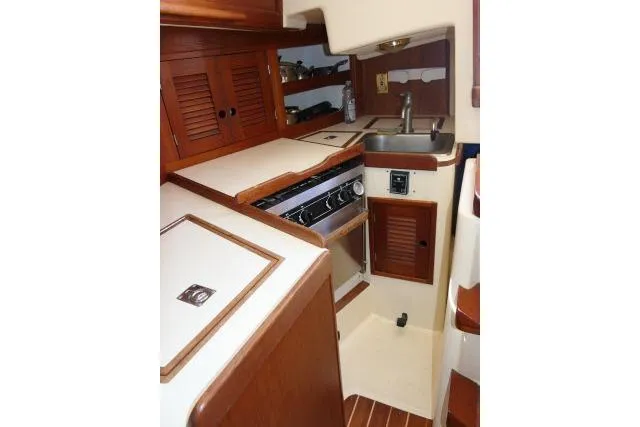 Slide: The Image of 1995 Tartan 3100 yacht interior kitchen with wooden cabinets and compact appliances. - 13