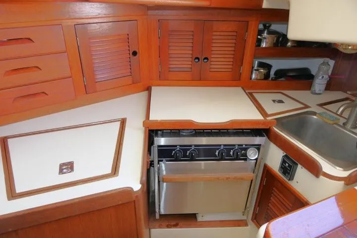Slide: The Image of 1995 Tartan 3100 yacht kitchen with wooden cabinets, stove, and sink. - 14