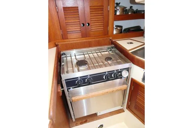Slide: The Image of Compact kitchen stove in a 1995 Tartan 3100 yacht galley with wooden cabinetry. - 15