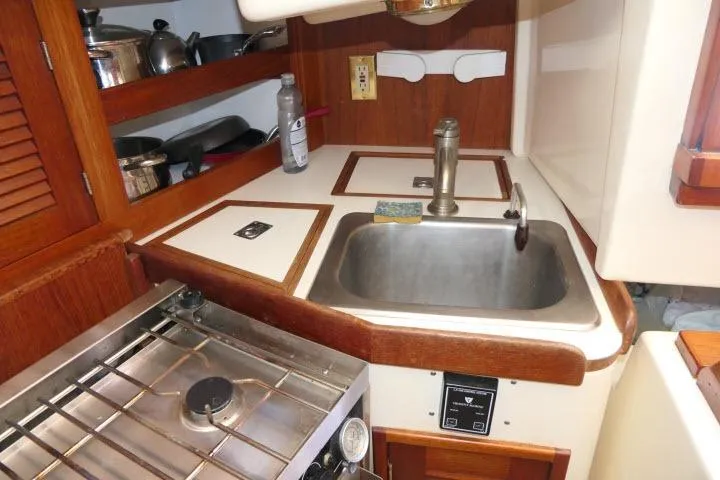 Slide: The Image of 1995 Tartan 3100 yacht kitchen with sink, stove, and wooden cabinetry. - 16