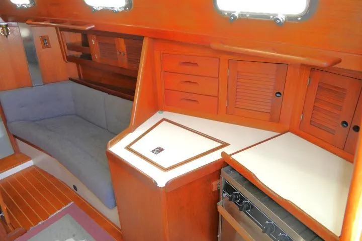 Slide: The Image of Interior of a 1995 Tartan 3100 sailboat with wooden cabinetry and cozy seating area. - 7