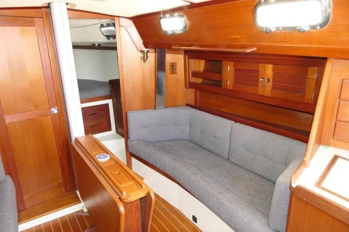 Slide: The Image of Interior of 1995 Tartan 3100 sailboat with wooden cabinetry and gray seating. - 8
