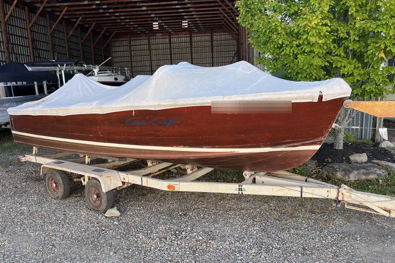 Slide: The Image of 1955 Chris-Craft 17 Cavalier boat on trailer, covered, in storage area. - 17