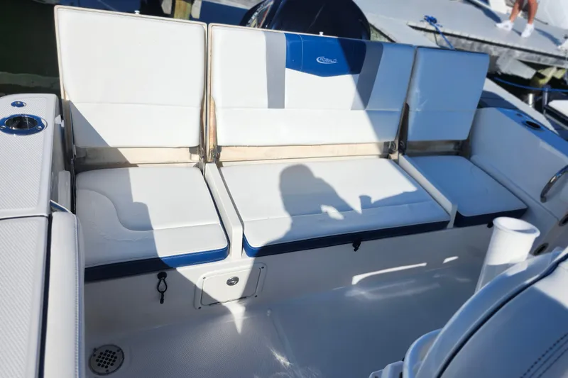 Slide: The Image of 2023 Robalo R230 Center Console boat seating area with white cushions and storage compartments. - 10