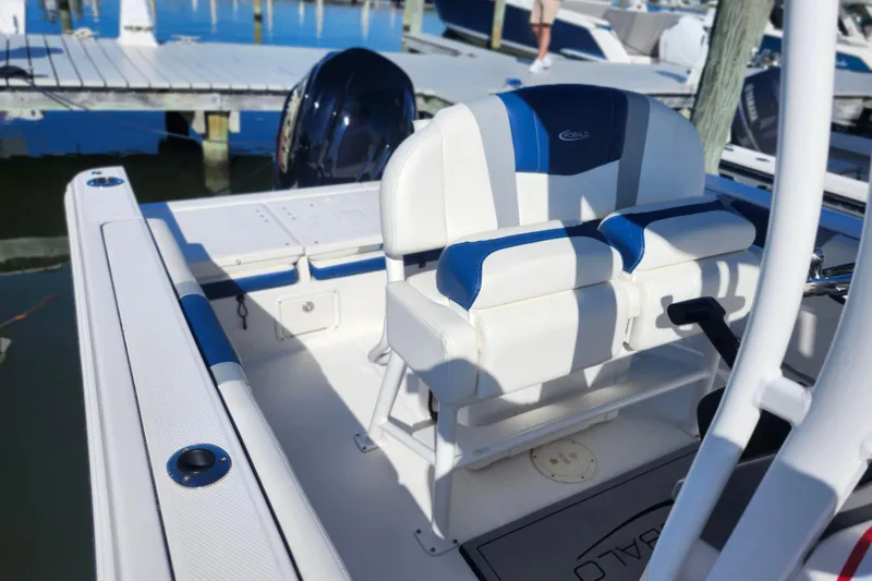 Slide: The Image of 2023 Robalo R230 Center Console boat interior with blue and white seating at a marina. - 9