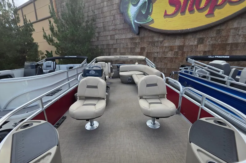 Slide: The Image of 2025 Sun Tracker Bass Buggy 18 DLX pontoon boat with beige seating, displayed outdoors. - 3
