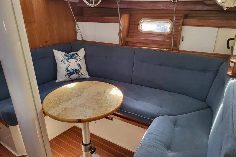 Slide: The Image of Cozy interior of 1993 Catalina 34 sailboat with blue seating and nautical-themed decor. Note the custom table. - 10