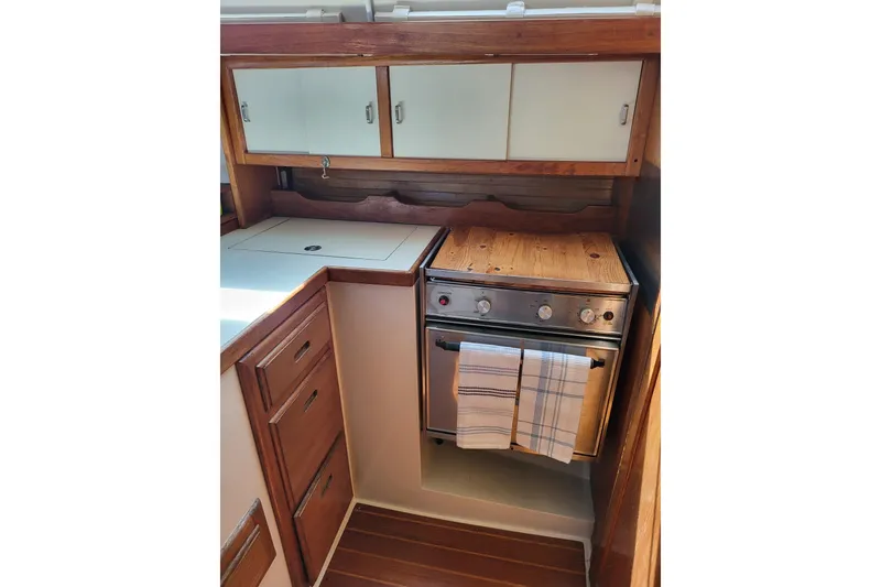 Slide: The Image of Galley in 1993 Catalina 34 sailboat with stove, cabinets, and wooden accents. - 11