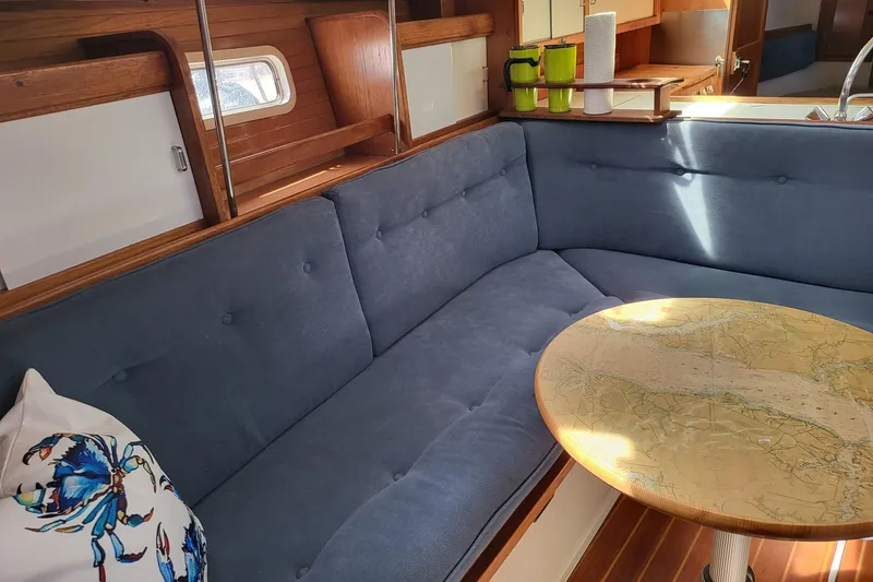 Slide: The Image of Interior of 1993 Catalina 34 sailboat with blue seating and map-themed table. - 12
