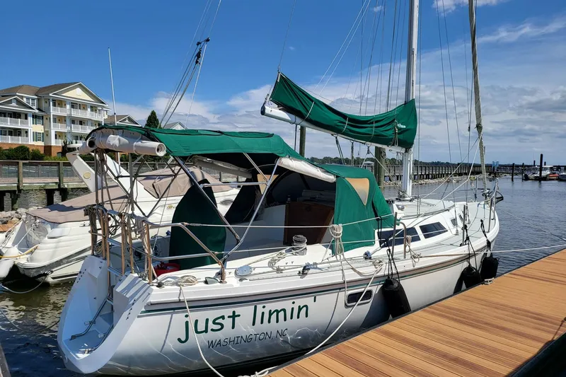 Slide: The Image of 1993 Catalina 34 sailboat docked, featuring green canvas covers, named "just limin'" in Washington, NC. - 2