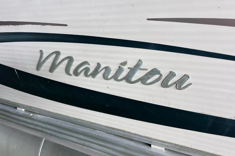 Slide: The Image of 2006 Manitou 24 Osprey pontoon boat on trailer, parked outside industrial building. - 3