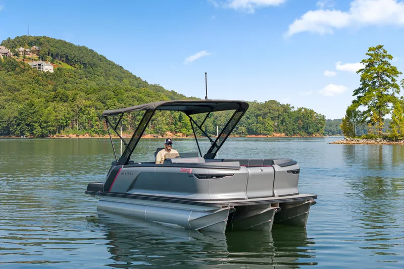 Slide: The Image of 2024 Manitou 22 Explore Max Bench pontoon boat on a scenic lake. - 1