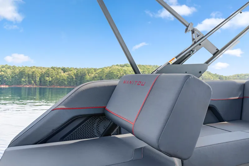 Slide: The Image of 2024 Manitou 22 Explore Max Bench boat interior with lake view, featuring sleek gray seating. - 10