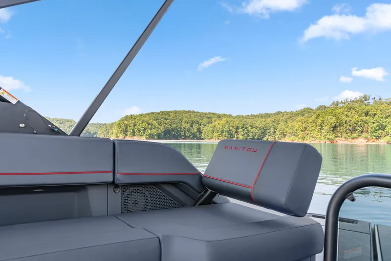 Slide: The Image of 2024 Manitou 22 Explore Max Bench boat interior with scenic lake view. - 8