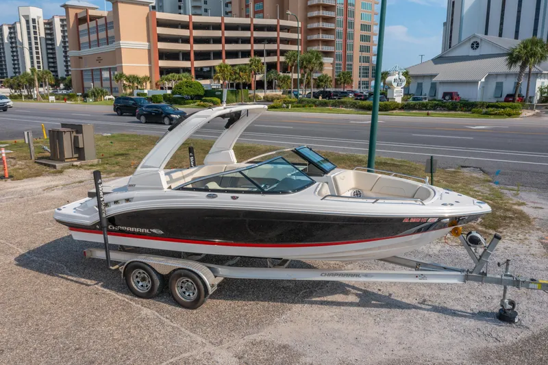 Slide: The Image of 2021 Chaparral 237 SSX boat on trailer, parked near urban buildings and road. - 2