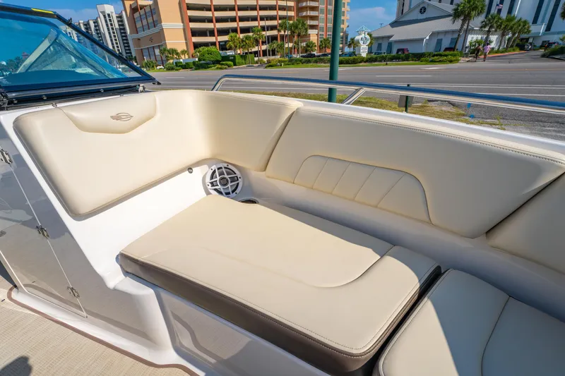 Slide: The Image of 2021 Chaparral 237 SSX boat interior with beige seating and speaker, docked near buildings. - 25