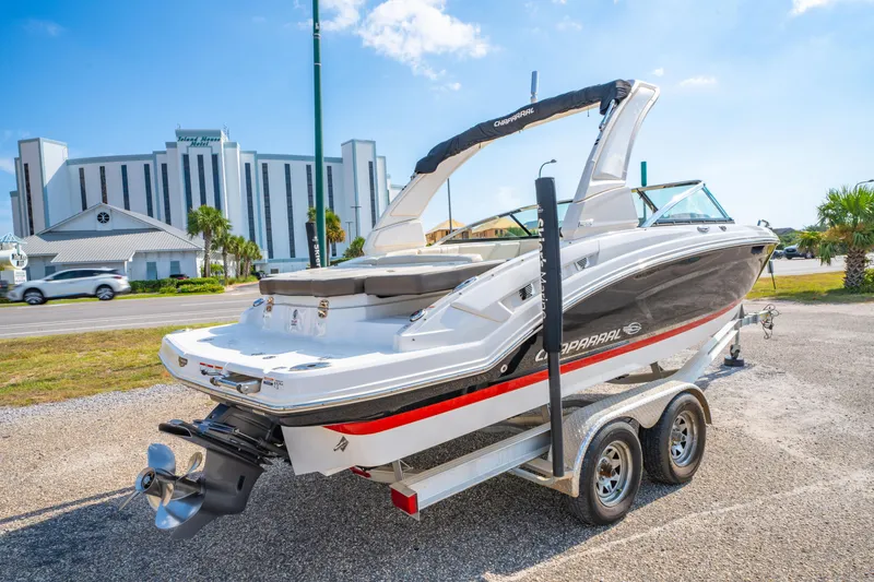 Slide: The Image of 2021 Chaparral 237 SSX boat on trailer, parked near a modern building under a clear sky. - 8