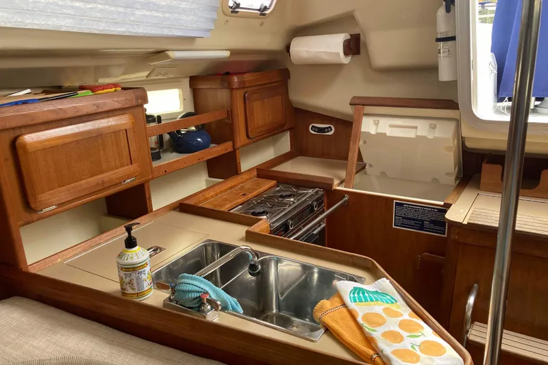 Slide: The Image of 1993 Hunter 33.5 yacht kitchen with wooden cabinets, sink, stove, and nautical decor. - 17