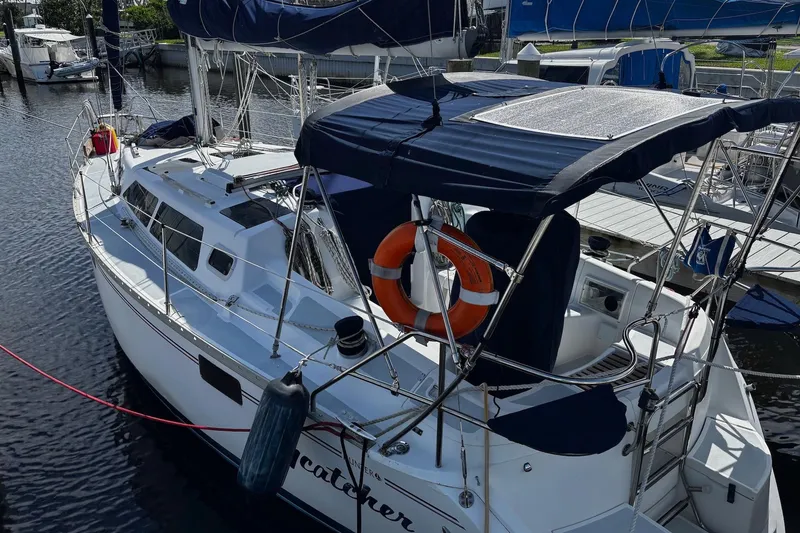 Slide: The Image of 1993 Hunter 33.5 sailboat docked, featuring blue canopy and life preserver. - 3