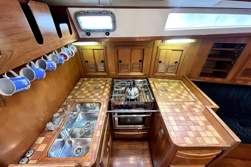 Slide: The Image of 1983 CT 38 Warwick yacht kitchen with wooden cabinetry, dual sink, and stove. - 11