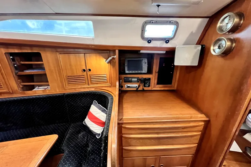 Slide: The Image of 1983 CT 38 Warwick yacht interior with wood cabinetry, navigation equipment, and cozy seating area. - 12