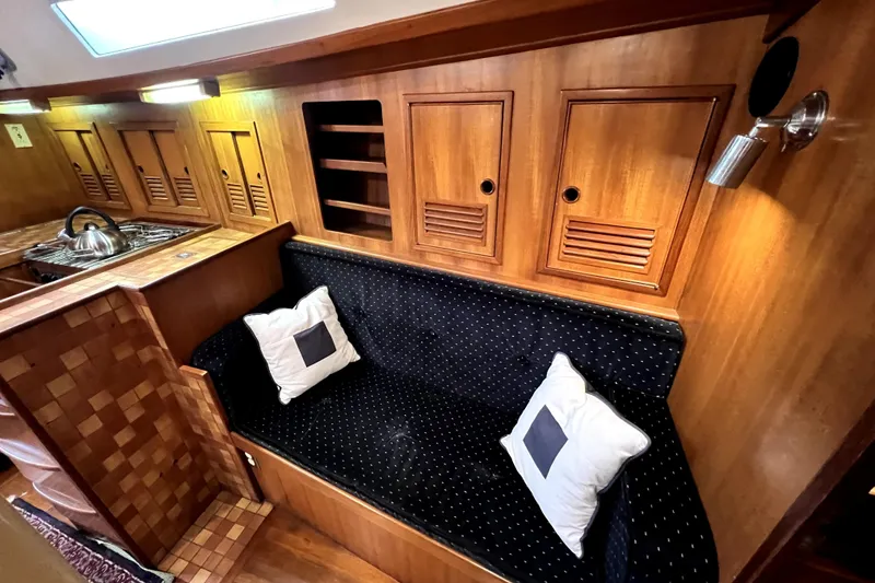 Slide: The Image of 1983 CT 38 Warwick yacht interior with wooden cabinetry, black cushioned seating, and kitchen area. - 14