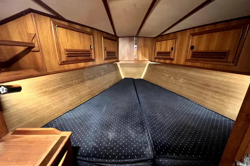 Slide: The Image of 1983 CT 38 Warwick yacht cabin with wooden interior and blue cushioned bedding. - 15