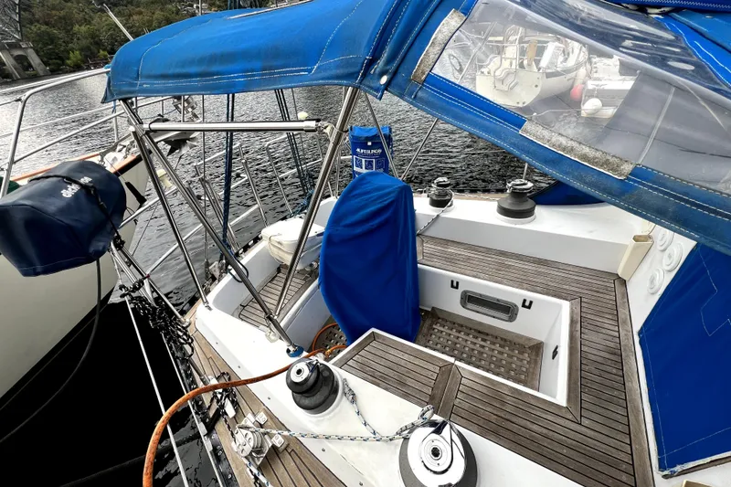 Slide: The Image of 1983 CT 38 Warwick sailboat cockpit with blue canopy and wooden deck, docked by the water. - 4