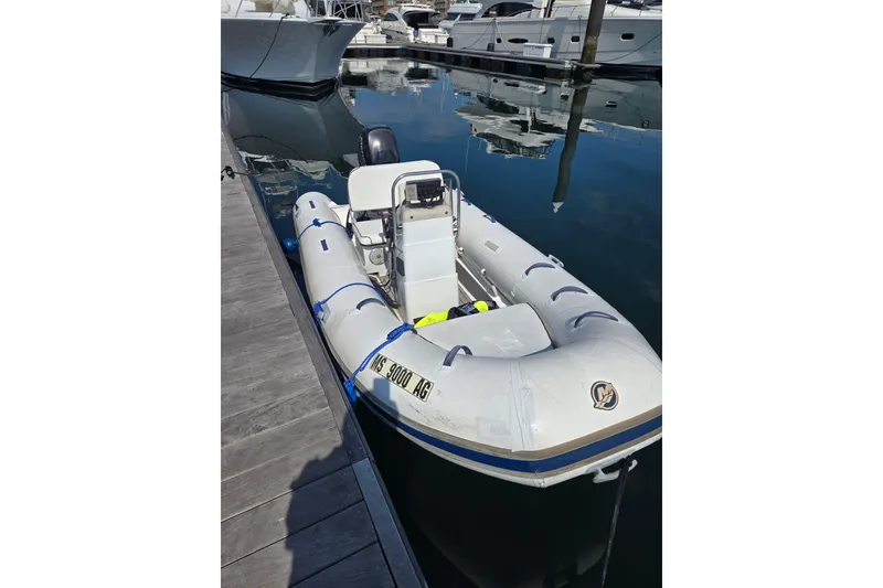 Slide: The Image of Inflatable Mercury Console boat, 2016 model, docked at marina with reflections on water. - 2