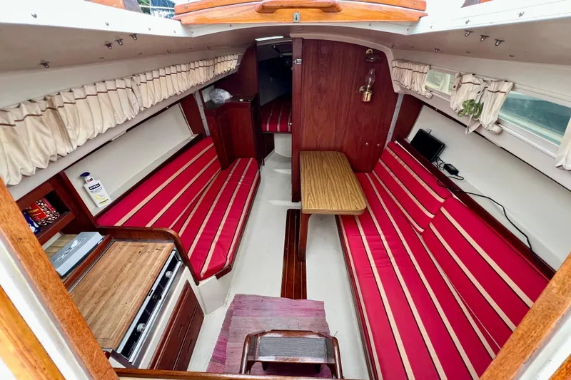 Slide: The Image of Interior of a 1985 Catalina 27 sailboat with red-striped seating and wooden accents. - 14