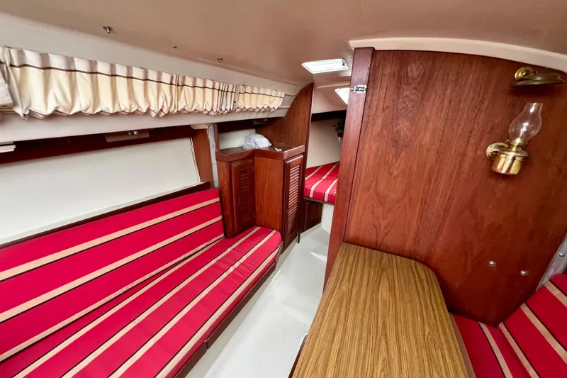 Slide: The Image of Interior of a 1985 Catalina 27 sailboat with red-striped seating and wood paneling. - 17
