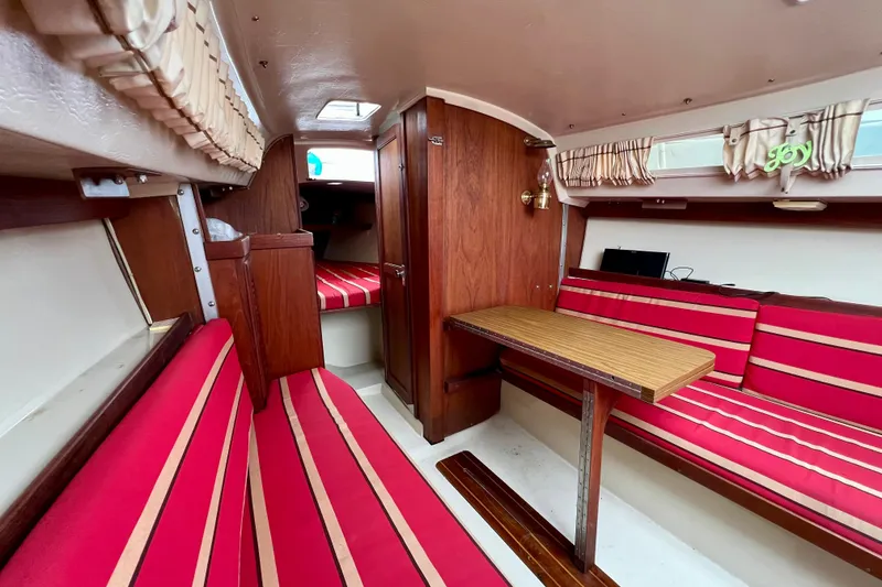 Slide: The Image of Interior of 1985 Catalina 27 sailboat with red-striped seating and wooden table. - 18