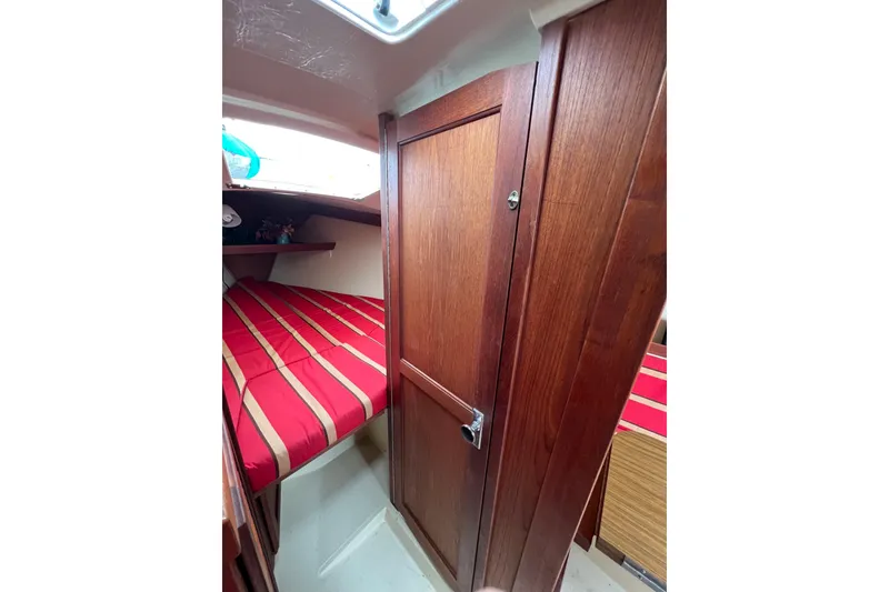 Slide: The Image of Interior of 1985 Catalina 27 sailboat with red-striped bedding and wooden cabinetry. - 19