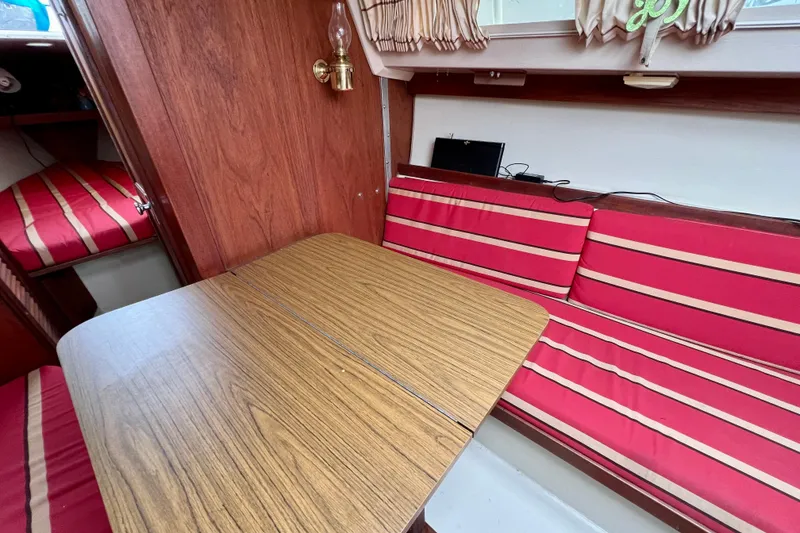 Slide: The Image of Interior of a 1985 Catalina 27 sailboat with red-striped seating and wooden table. - 24