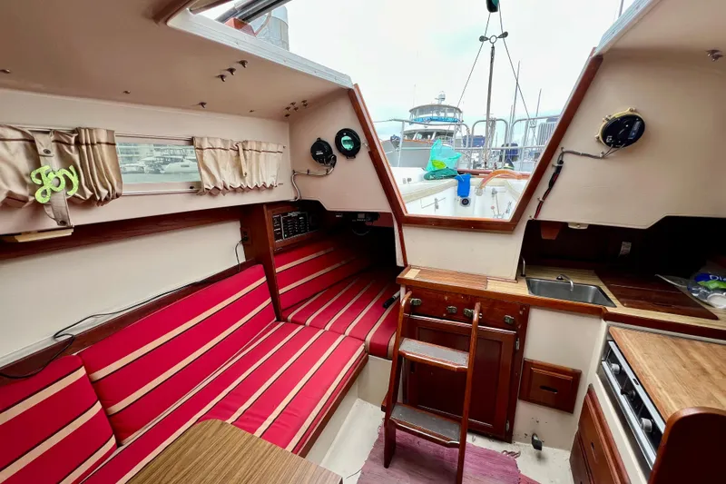 Slide: The Image of Interior of a 1985 Catalina 27 sailboat with red-striped seating and wooden cabinetry. - 26