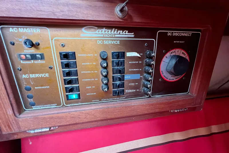 Slide: The Image of Electrical panel of a 1985 Catalina 27 yacht with AC and DC service controls. - 28