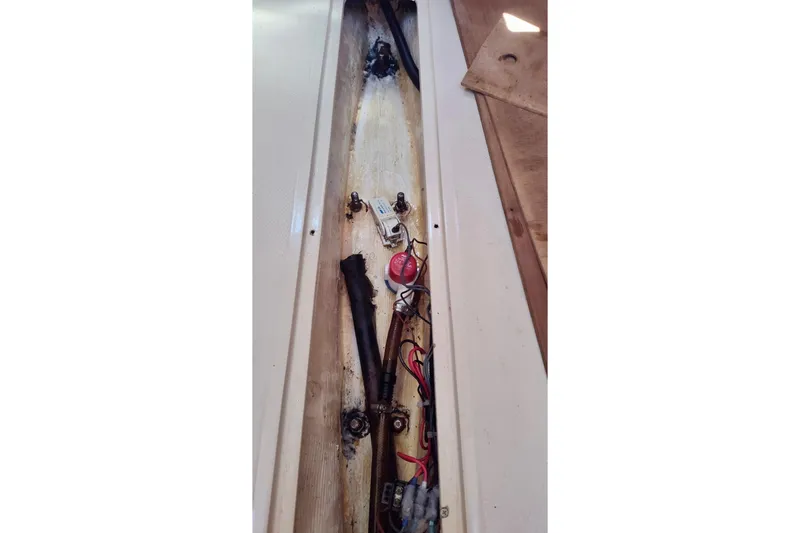 Slide: The Image of 1985 Catalina 27 interior wiring and components in a narrow compartment. - 32