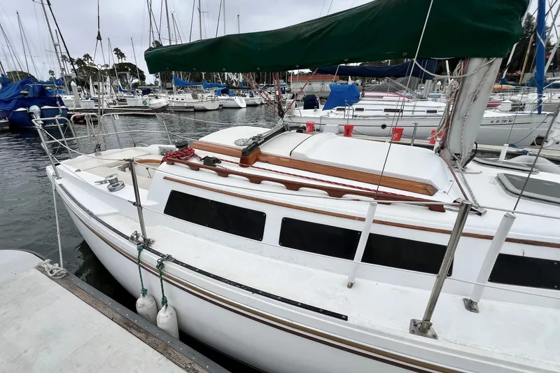 Slide: The Image of 1985 Catalina 27 sailboat docked in a marina, featuring a green sail cover. - 6