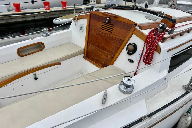 Slide: The Image of 1985 Catalina 27 sailboat cockpit with wooden accents and red rope, docked at marina. - 8