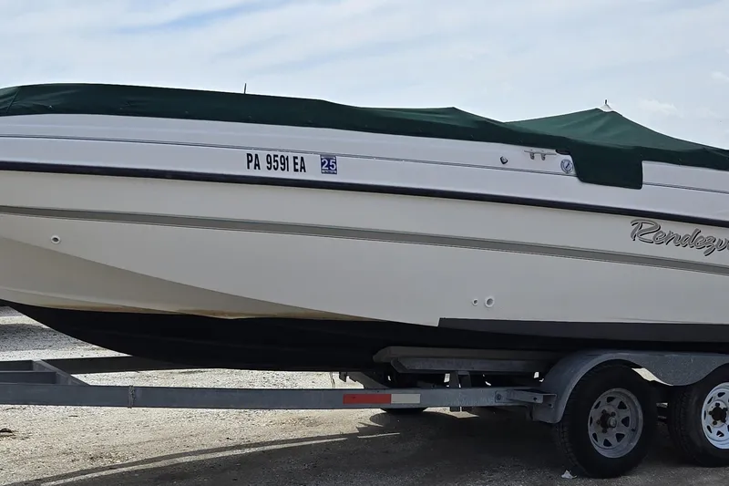 The Image of 1999 Bayliner 2459 Rendezvous DX/LX boat on trailer, covered with green tarp. - 0
