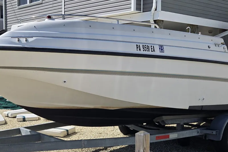 Slide: The Image of 1999 Bayliner 2459 Rendezvous DX/LX boat on trailer, parked near a building. - 14